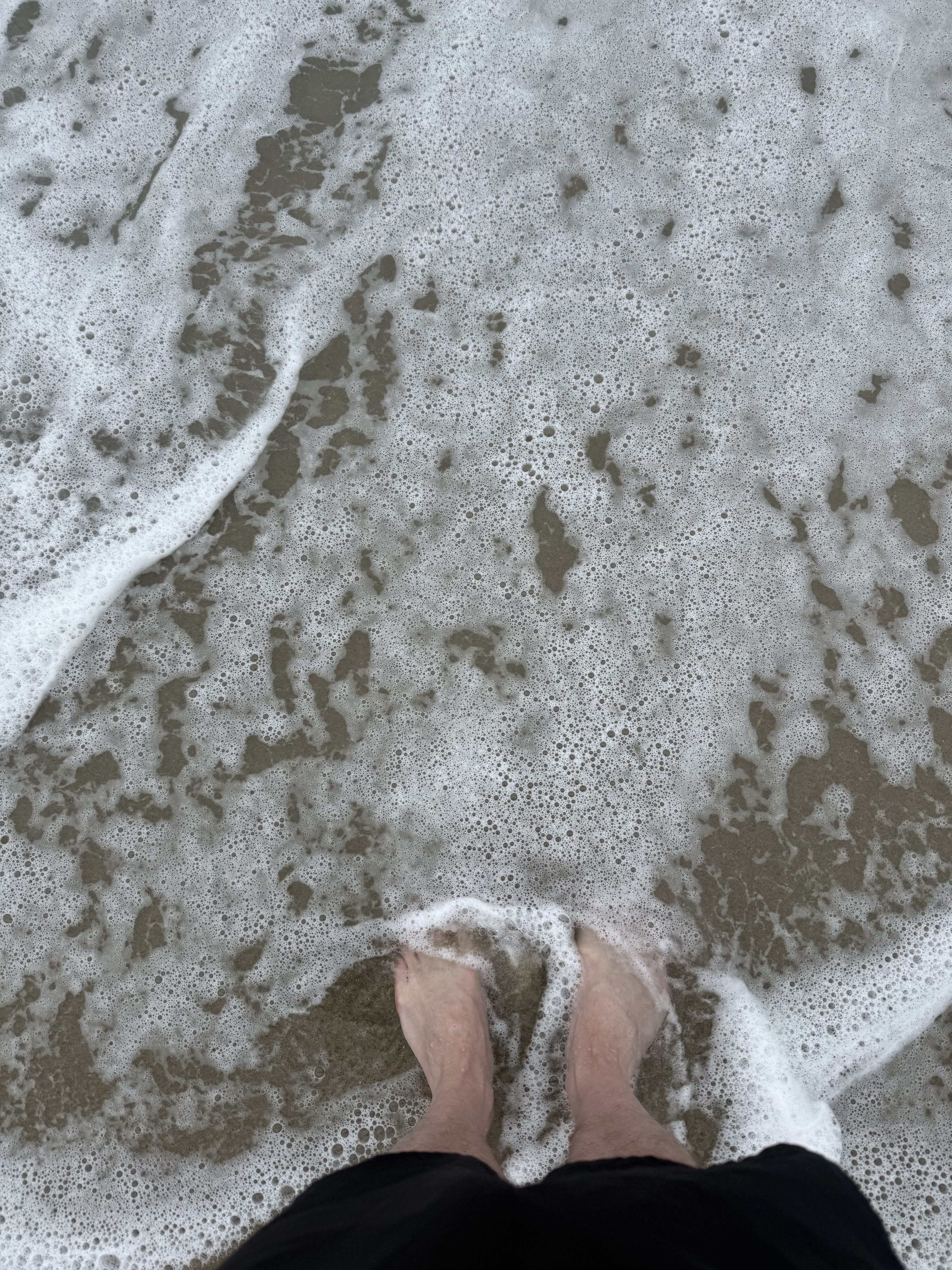 Feet in foamy ocean surf