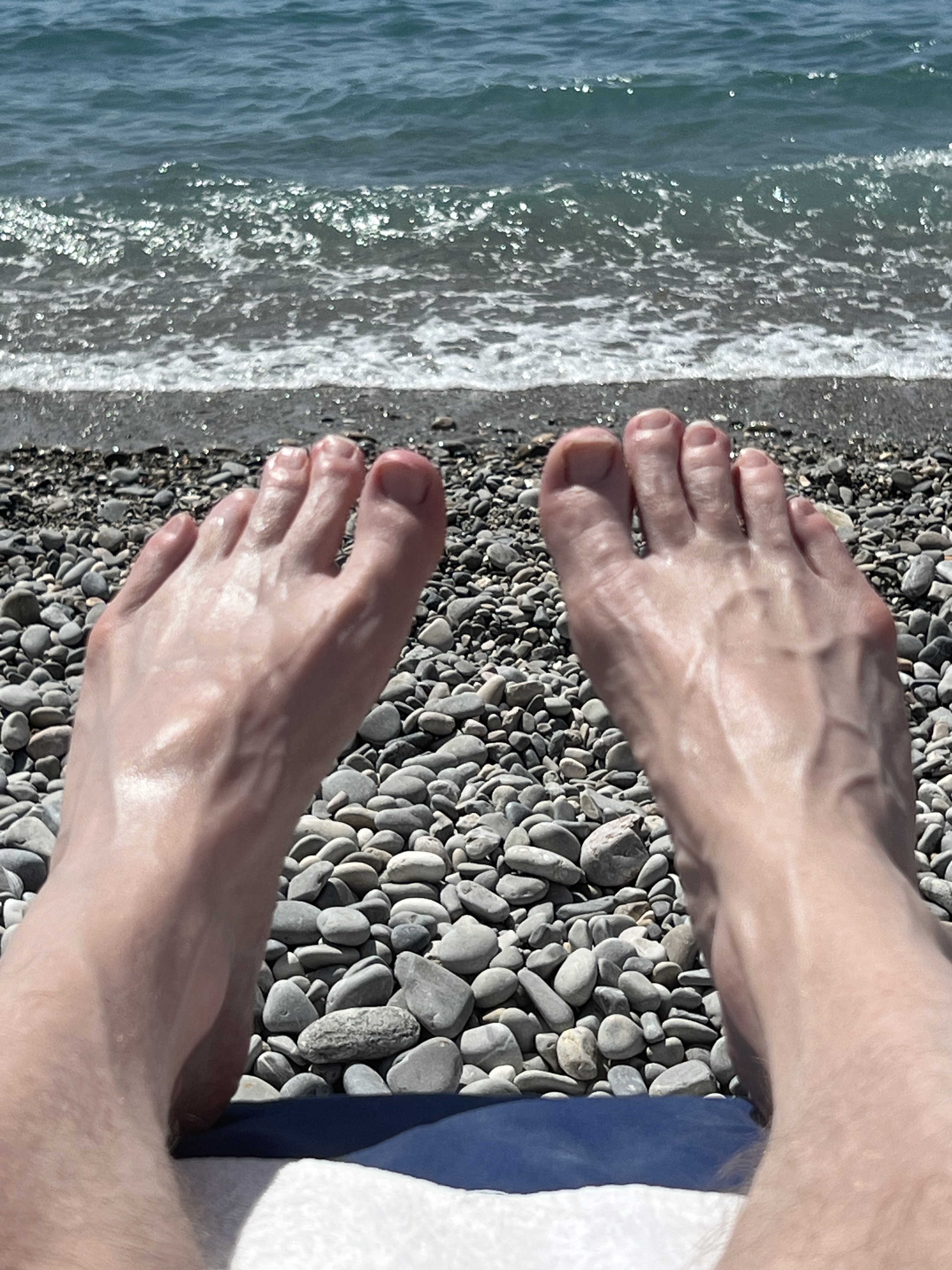 Feet on a pebble beach, sea in background